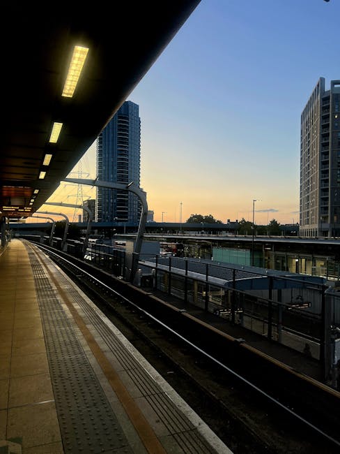 The image shows the exterior entrance of Hanwell underground station, part of the Elizabeth Line, with a person standing on the pavement facing towards the station's black entrance canopy that display